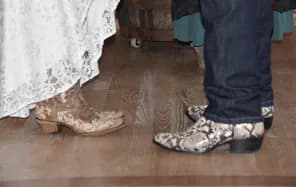 Western boots peeking out from under the bride's gown