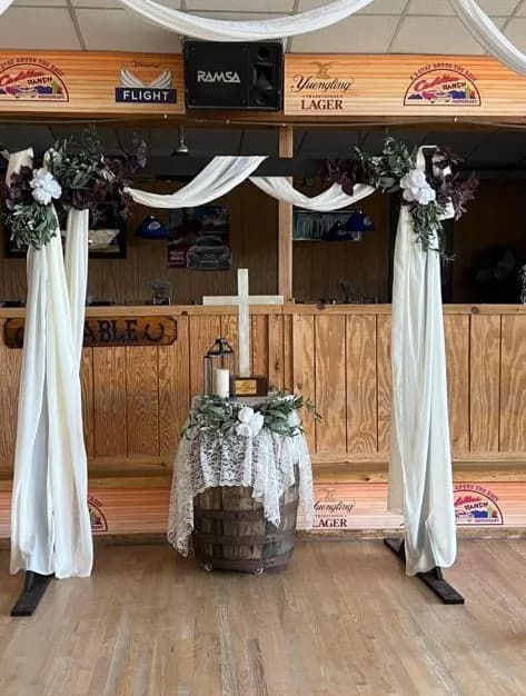 A draped wedding ceremony arch with florals and a wine-barrel altar set up inside Cadillac Ranch