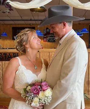 Newlyweds sharing a kiss on the dance floor, the bride holding her bouquet